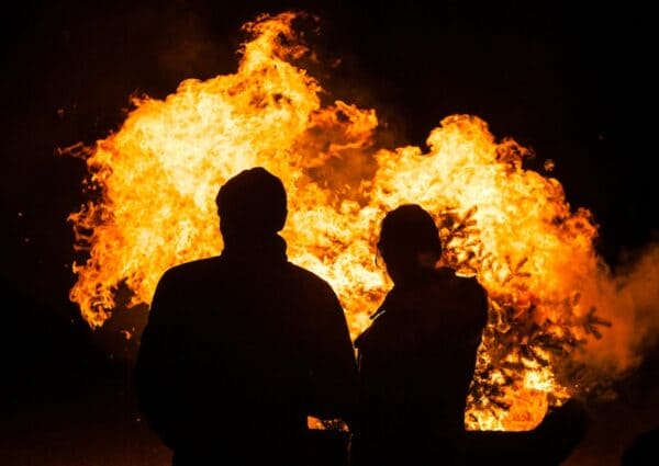 The House Catches Fire. What Do You Do? Two people standing in front of a fire