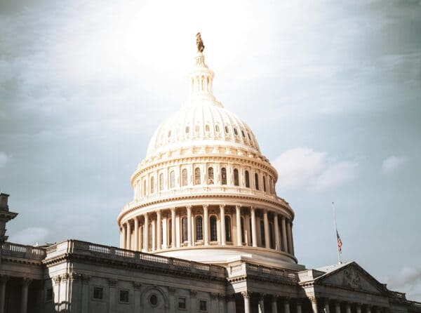 Do The Spirits Care About The Senate? U.S. Capitol dome under a bright sky with an American flag nearby, symbol of the U.S. government. ∴ WholeSpirit